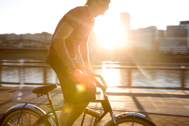 Mann fährt Fahrrad bei Sonnenuntergang auf einer Brücke